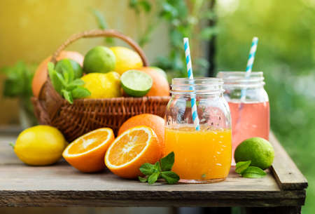 Mix of fresh citrus fruits in basket and juice in glass jars. Grapefruit and orange juiceの写真素材