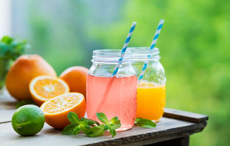 Grapefruit and orange juice in glass jars in the open air. Concept for healthy eating and nutrition. Selective focus.の写真素材