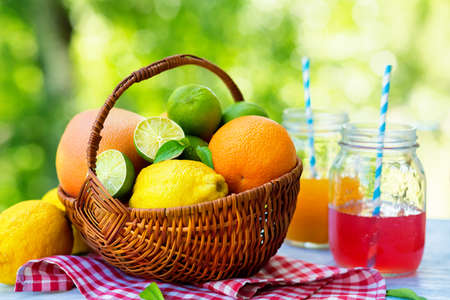 Mix of fresh citrus fruits in basket and juice. Refreshing summer drink.の写真素材