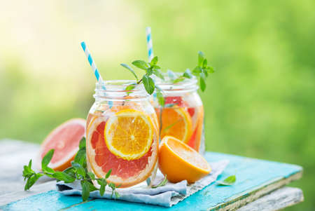 Grapefruit and orange water in glass jars in the open air. Concept for healthy eating and nutrition. Copy space.の写真素材