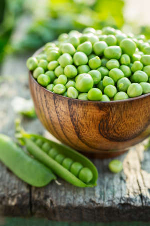Fresh green peas in a bowl on old tableの写真素材