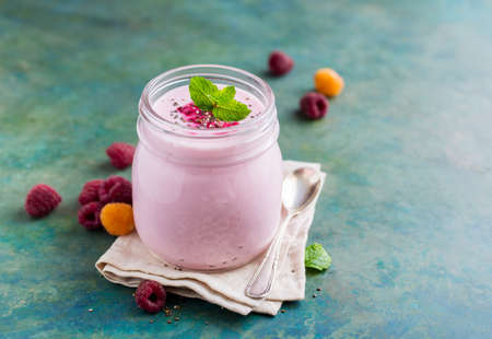 Natural homemade yogurt in a glass jar with raspberry and mint, selective focus, copy spaceの写真素材
