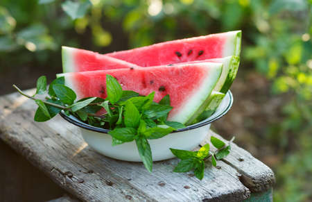 Fresh sliced watermelon in a white bowl outdoors.の写真素材