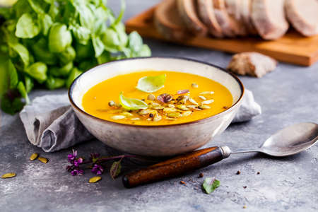 Pumpkin soup in a bowl with basil leaf and pumpkin seeds. Autumn food.の写真素材