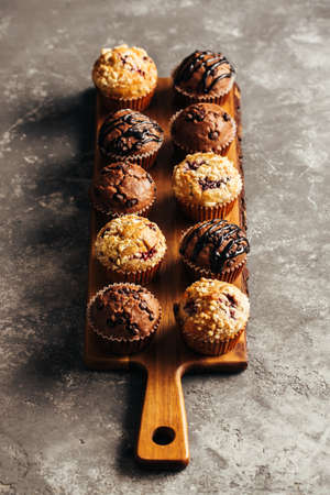Berry and chocolate muffins on a wooden boardの写真素材