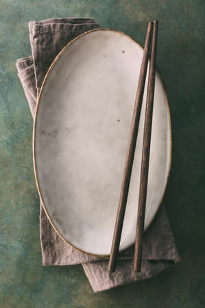 Empty oval dish and chopsticks. Background with copy space.の写真素材