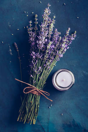 Fresh bundle of lavender and scented candle on a blue background.の写真素材