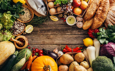 Different foods on a wooden background wiht copyspace. Various fruits and vegetables, fish, bread and eggs.の写真素材