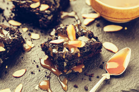 Homemade dark chocolate brownies with caramel and almond flakes, close up. Selective focus.の写真素材