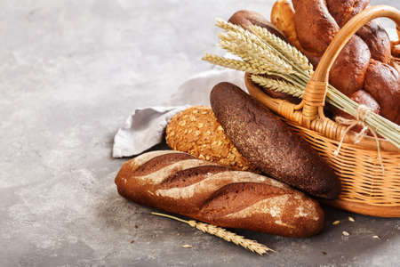 Different fresh bread in the basket on a grey background with copy space.の写真素材