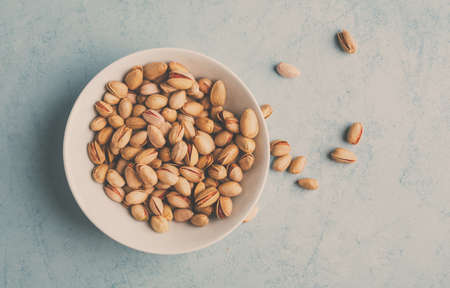 Roasted pistachios in a bowl, delicious snack. Top view. Toned image.の写真素材