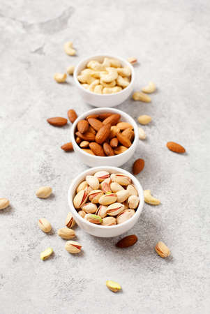 Fresh organic nuts, almonds, cashew, pistachio in a bowls on a light background.の写真素材