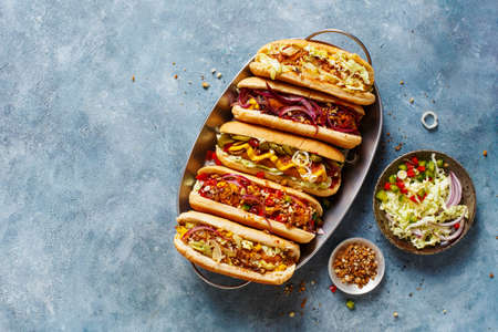 Different tasty hot dogs on a tray on a blue surface with copy space., top view.の写真素材