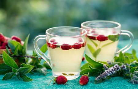Two cups of hot tea with strawberry and mint. Outdoor.の写真素材