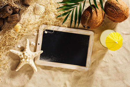Summer vacation template background with empty blackboard on the sand. Top view with copy space.の写真素材