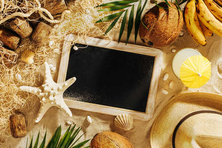 Summer vacation template background with empty blackboard and beach accessories on the sandの写真素材