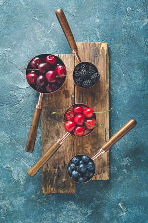 Different berries in copper measuring cups, toned.の写真素材