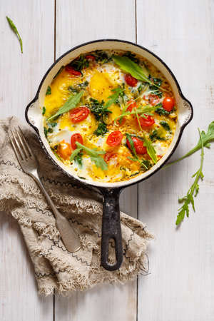 Fried eggs with spinach and tomatoes, top view.の写真素材