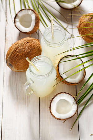 Coconut juice in jars on a white wooden boardの写真素材