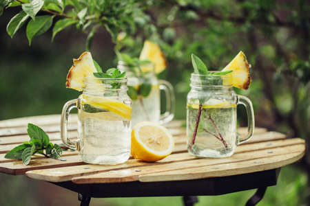 Detox water with lemon and mint in jars on the garden table.の写真素材