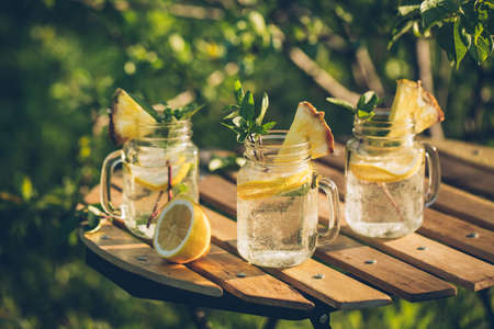 Refreshing chilled lemon water on the garden table. Selective focus.の写真素材