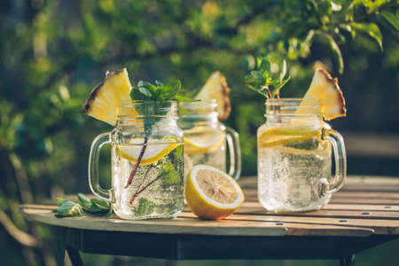 Detox water with lemon and mint in jars on the garden table. Selective focus.の写真素材