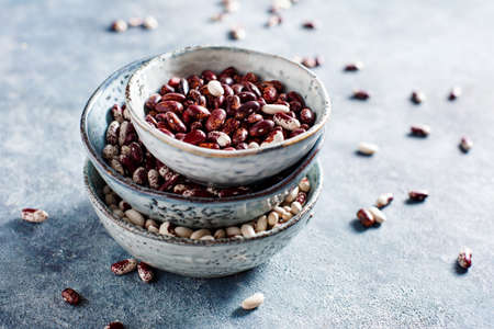 Different types of beans in bowls on a blue background. Selective focus.