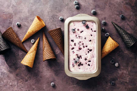 Homemade Ice cream with blueberries in a metal container and waffle cones, top view.の写真素材