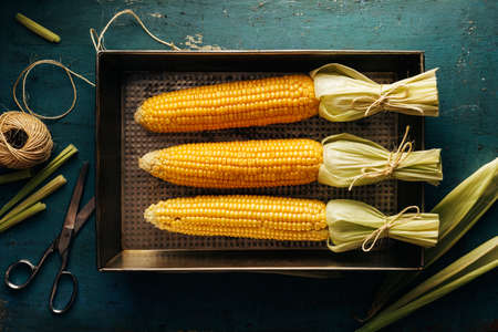 Fresh corn cobs on a baking tray. Top view. Selective focus.の写真素材