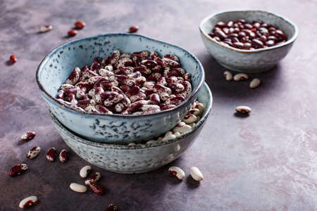 Different types of beans in bowls on a purple background. Selective focus.の写真素材