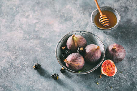 Fresh figs and honey in a bowl.の写真素材