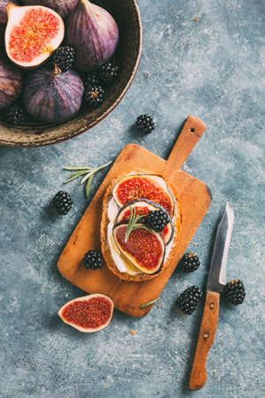 Sandwich with fresh figs, blackberries and honey on a little cutting board. Top view.の写真素材