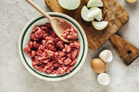 Fresh raw minced pork in a bowl with ingredients for cooking on a black kitchen table. Minced meat. Top view.の写真素材