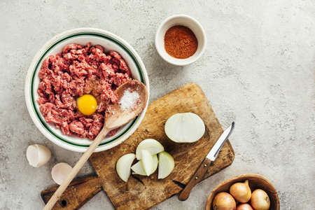 Fresh raw minced beef in a bowl with ingredients for cooking on a black kitchen table. Minced meat. Top view.の写真素材