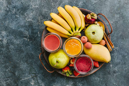 Delicious smoothies in jars with bananas, strawberries and tropical fruit. Top view. Copy spaceの写真素材