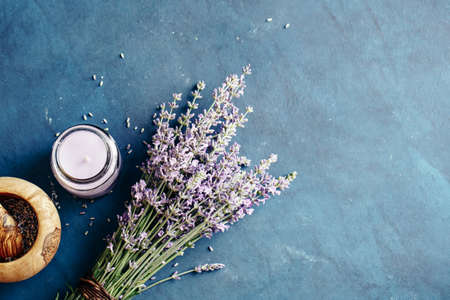 Fresh bundle of lavender and scented candle on a blue background.の写真素材