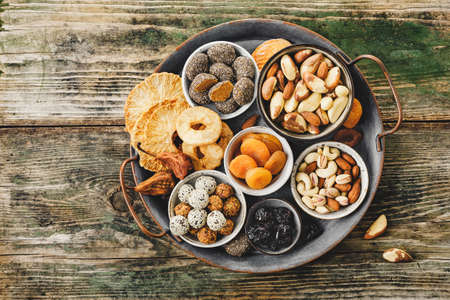 Mix of nuts and dried fruits on a old metal tray, rustic wooden table. Top view.の写真素材