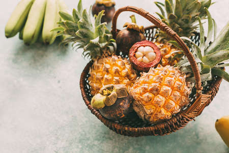 Ripe tropical fruits in a basket, pineapples, mangosteen.の写真素材