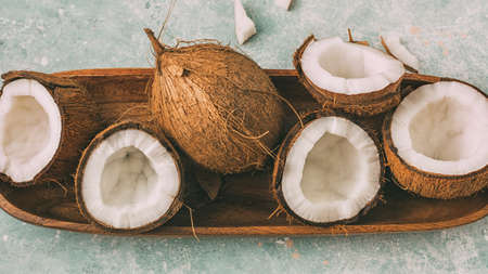 Fresh coconuts with coconut halves on a tray, close-up, top view.