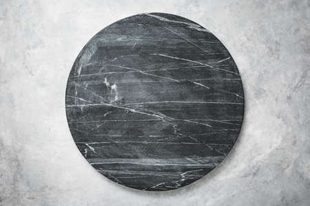 Round slab of black marble on a grey texturedの写真素材