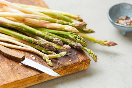 Freshly picked asparagus on a cutting Board, salt, pepper. The concept of healthy eating. Selective focus.の写真素材