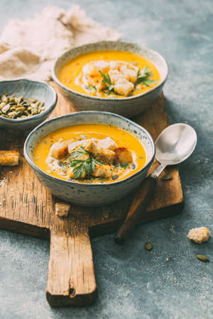 Two bowls of warm pumpkin soup with croutons and spices.の写真素材
