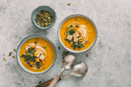 Two Bowls of delicious autumn pumpkin soup with croutons, top view.の写真素材