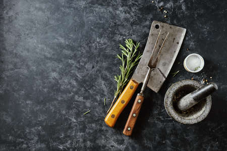 Vintage Meat cleaver with fork and spices on a dark background. Top view, Copy spase.の写真素材