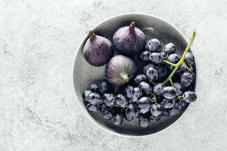 Organic whole figs and grapes in a bowl. Top view, copy space.の写真素材