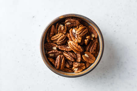 Peeled pecan halves in a bowl, on white background. Close up,Top view.