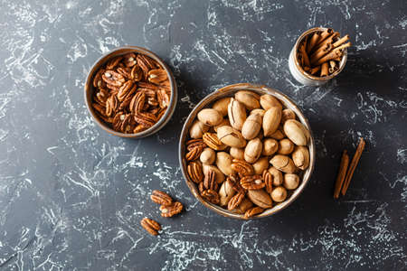 Fried pecan in bowls and cinnamon, on dark background. Top view.の写真素材