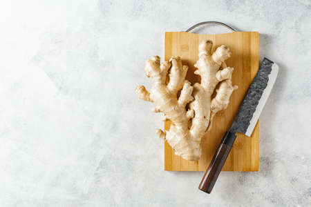 Fresh ginger root on a cutting board, copy space, top view.