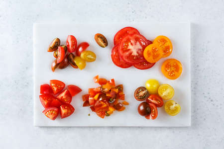 Red and yellow cherry tomatoes on the white marble board, up view.の写真素材
