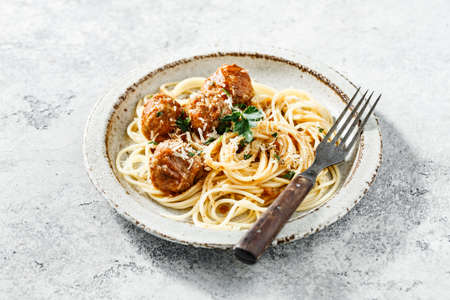 Homemade spaghetti and meatballs served with fresh herbs and parmesan cheese.の写真素材